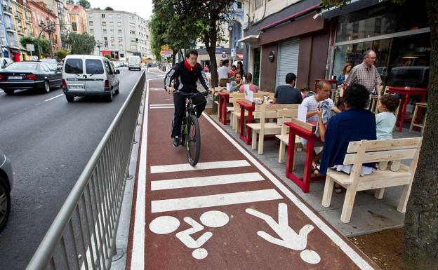 Una terraza hostelera linda con el carril bici en la calle de Casimiro Sainz. Los ciclistas están protegidos de los coches por una barandilla.