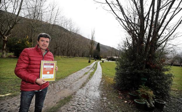 José María Mier, a la entrada del camping, sujeta el diploma que acredita su premio./Javier Rosendo