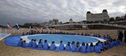 Varios escolares mostraron por primera vez el logo de la candidatura en la Primera playa de El Sardinero. / CELEDONIO/