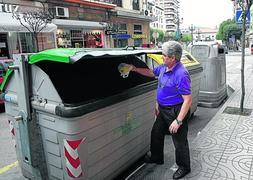Un vecino de Torrelavega deposita basura junto a contenedores de reciclaje en la céntrica calle Ruiz Tagle. / Luis Palomeque/