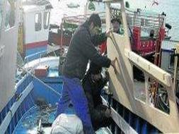 Dos operarios sustituyen el puente de un pequeño barco de pesca por otro nuevo. Las reparaciones y reformas de barcos son habituales en Astilleros Ruiz. / SANE/